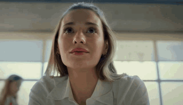 a woman in a white shirt is looking up in a room