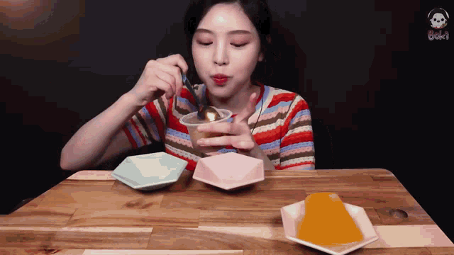a woman is sitting at a table eating something with a spoon in her mouth