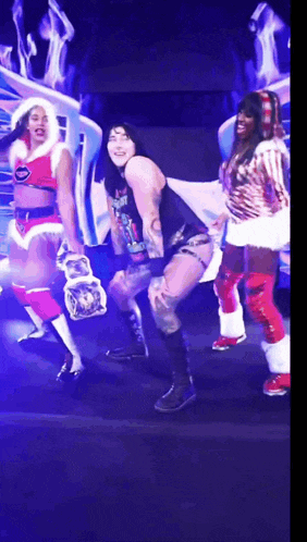 a man in a black tank top is dancing with two women in santa costumes