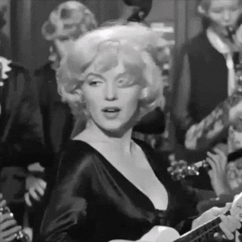 a woman in a black dress is playing a guitar in front of a band