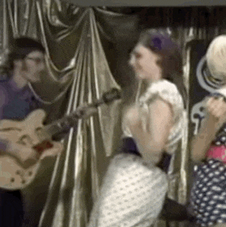 a man is playing a guitar and a woman is dancing in front of him .