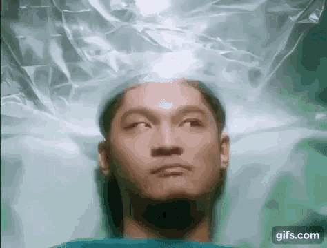 a man is laying in a plastic bag with his eyes closed