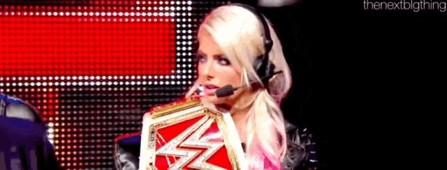 a woman wearing a headset is holding a wrestling championship .