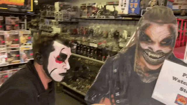 a man in a clown costume is standing next to a cardboard cutout of a man with a skull on his face