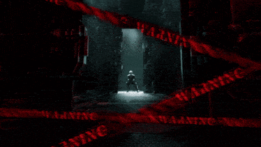 a man is standing in a dark hallway with a warning sign