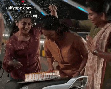 three women are celebrating a birthday on a motorcycle .