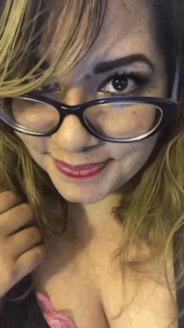 a woman wearing glasses and a pink bra smiles for the camera