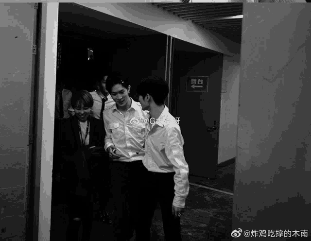 a black and white photo of a group of people standing in a hallway with a sign that says ' exit '