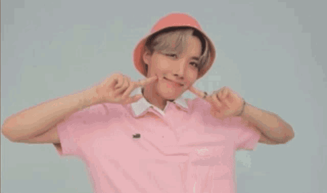 a young man wearing a pink hat and a pink shirt is smiling .