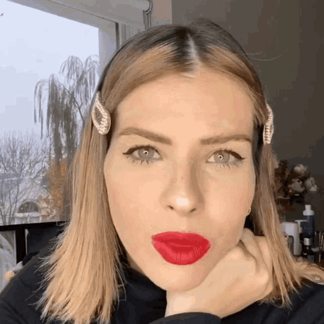 a woman with red lipstick and a hair clip on her head