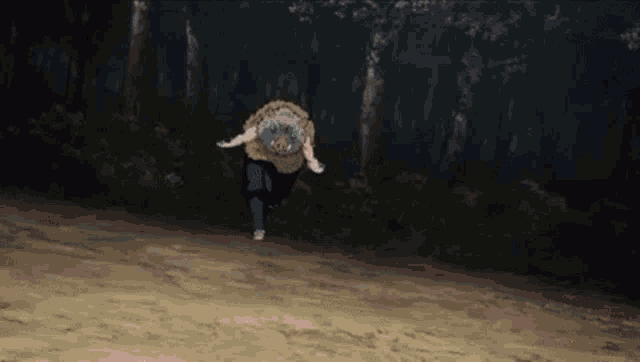 a man is running through a forest with a sheep on his back .