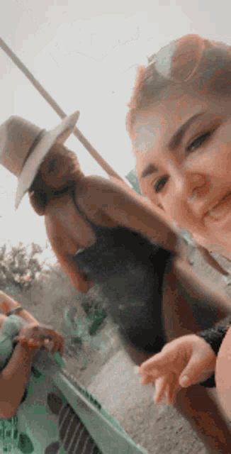 a woman wearing a straw hat is standing next to another woman wearing a swimsuit