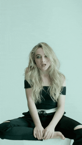a blonde woman is sitting on the floor with her legs crossed and her mouth open