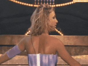 a woman in a purple dress is dancing on a stage with the words trendizisst written on the bottom