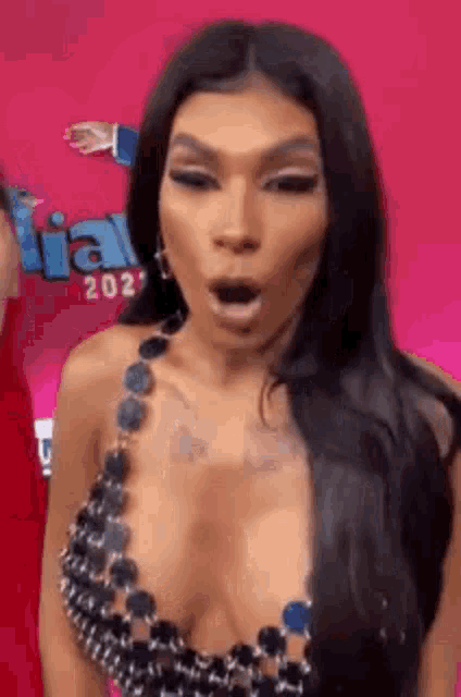 a woman in a very revealing top is making a funny face with her mouth open .