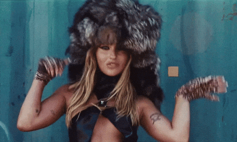 a woman wearing a fur hat and gloves has a tattoo on her arm that says gs