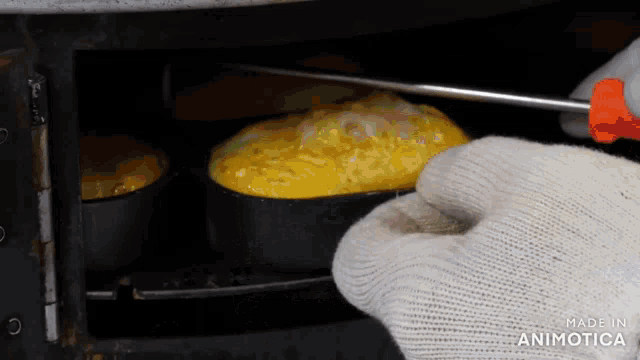 a person wearing a white glove is holding a screwdriver over a pan of food with the words made in animotica visible