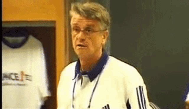a man in a white adidas jacket is standing in front of a row of shirts with france on them