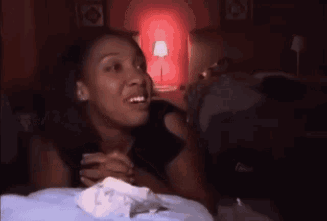 a woman is laying on a bed with a napkin in her hand and smiling .