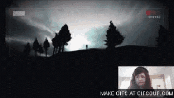 a woman is sitting in front of a screen with a silhouette of trees in the background .
