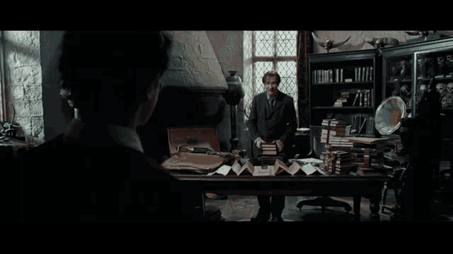 a man in a suit and tie stands in front of a wooden desk