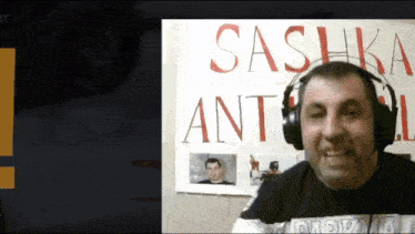 a man wearing headphones is standing in front of a sign that says sashka ant