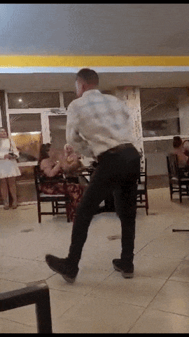 a man in a white shirt is dancing in a room