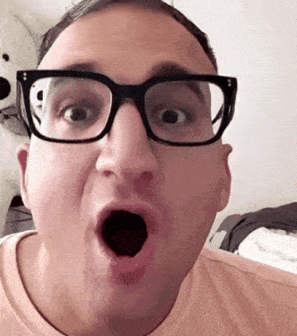 a man wearing glasses makes a surprised face with his mouth open