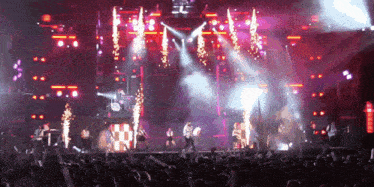 a crowd of people watching a concert with purple lights and smoke coming out of the stage