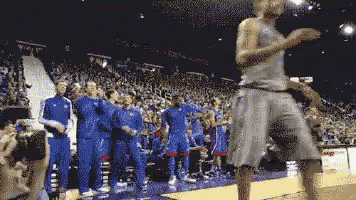 a group of basketball players in blue uniforms are dancing on the court