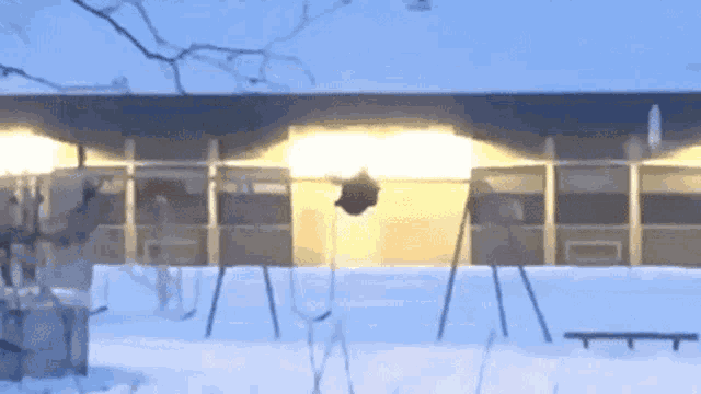 a swing set in the snow in front of a building .