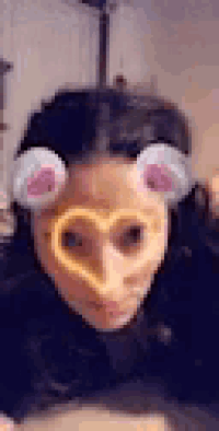 a woman is wearing a heart shaped mask with ears and a heart shaped nose .