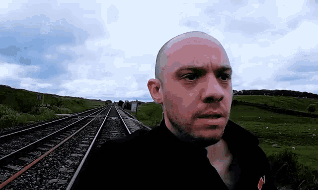 a man standing on train tracks with a serious look on his face