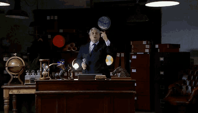 a man in a suit is holding a globe in his hand