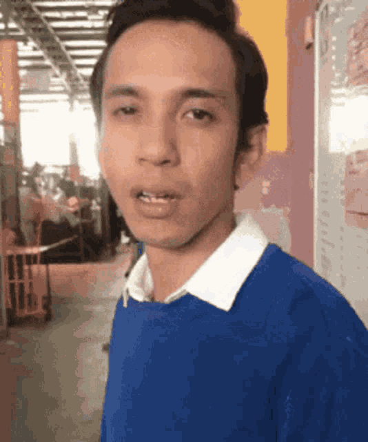 a man wearing a blue sweater and a white collar