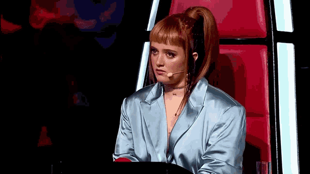 a woman with red hair is sitting in a chair with a microphone on her head
