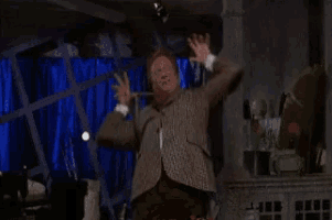 a man in a suit is dancing in a room with blue curtains .