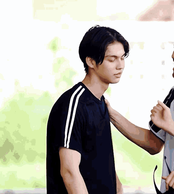a man in a black shirt with white stripes on the sleeves is being touched by another man