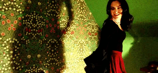 a woman in a red skirt is smiling in front of a green wall