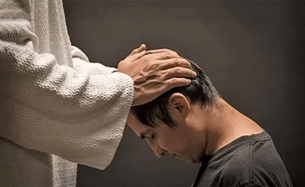 a man is praying to jesus with his hands on his head