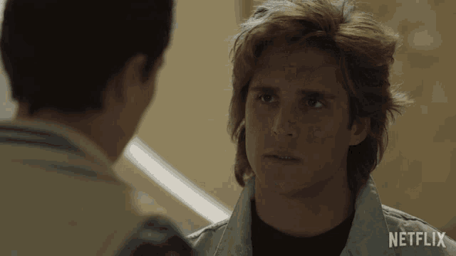 a man talking to another man with netflix written on his shirt