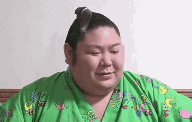 a sumo wrestler in a green shirt with the letter p on it