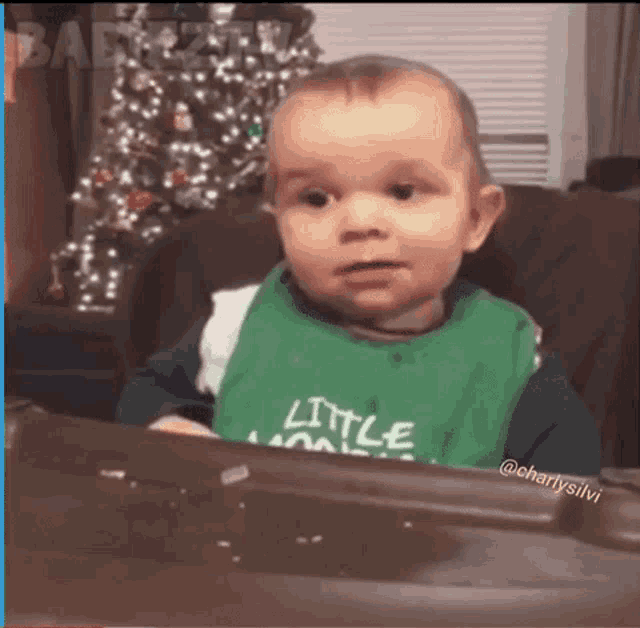 a baby in a green bib is sitting in a high chair .