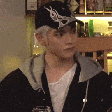 a man wearing a hat and a hoodie is standing in front of a bar .