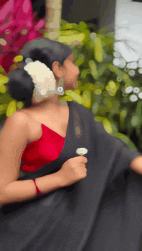 a woman with a flower in her hair is wearing a black saree