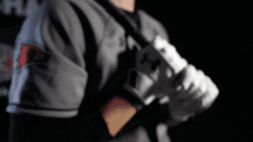 a baseball player is holding a bat and wearing gloves with the letter x on them