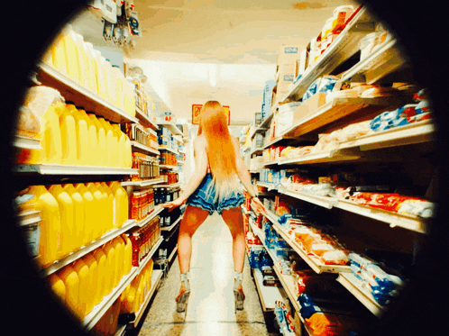 a woman is standing in a grocery store aisle with a sign that says ' coca cola ' on it