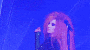 a woman with red hair is singing into a microphone on stage