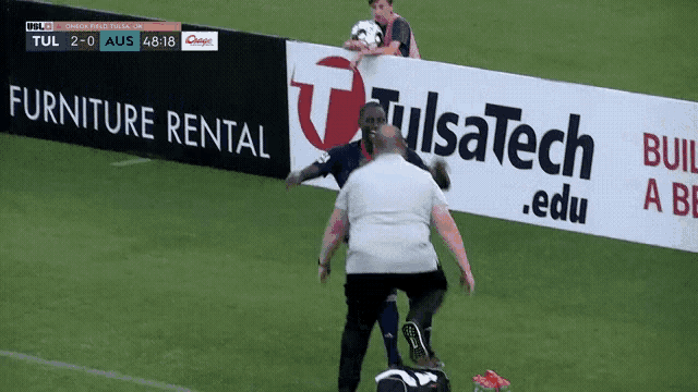 a soccer game is being played in front of a tulsatech advertisement