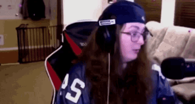 a woman is wearing headphones and a hat while sitting in a chair .